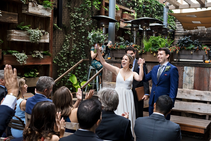 A bride and groom cheer with their wedding guests at their ceremony at Talula's Garden in Philadelphia.